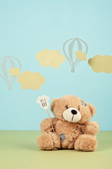 Cute teddy bear over the blue pastel background with clouds and ballons