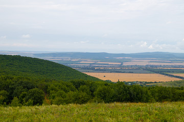 Obraz premium Southern highlands. Field with low mountains. Low mountains with trees. Anapsky district, Russia. Summer mountain landscape