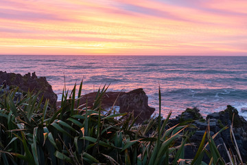 The sky is ablze with colour during a sunset at the famous Pancake rocks on the West coast of New Zealand