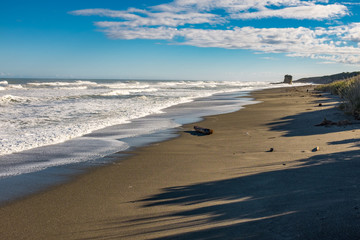 An empty beach at the end of a sunny day, long shadows starting to fall