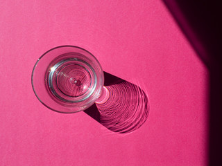 empty glass with deep shadow on pink
