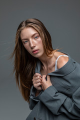 Portrait of slim model in grey jacket flashing underwear isolated grey background