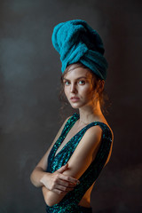 Portrait of young woman in turquoise sparkled dress with towel wrap isolated grey background