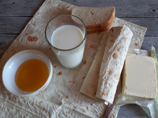 On the table, homemade wholesome food: milk, honey, butter, bread.