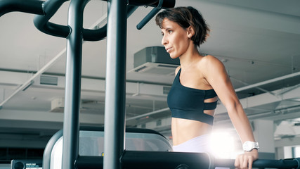 Athletic woman in sportswear is doing push-ups on parallel bars in gym. Sport and bodybuilding...