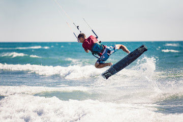 Naklejka premium Professional kiter makes the difficult trick on a beautiful background. Kitesurfing Kiteboarding action photos man among waves quickly goes