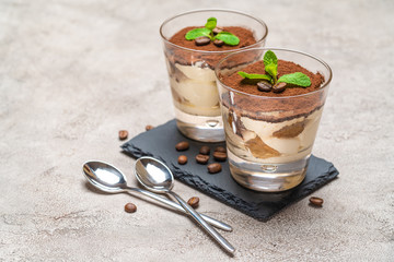 Classic tiramisu dessert in a glass on stone serving board on concrete background