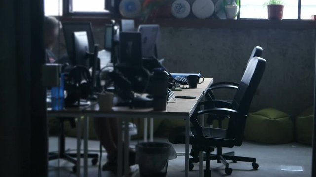 Young office worker, sitting at table, works at a computer in an modern office building