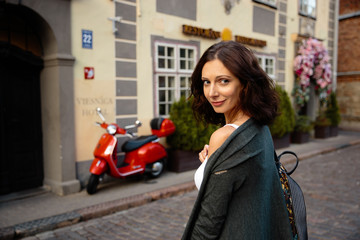 Happy woman portrait sexy moving on red motorcycle bike background in beautiful Riga old town