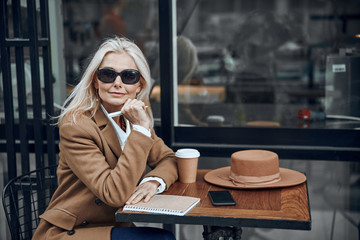 Fototapeta premium Mature woman with notebook in cafe stock photo