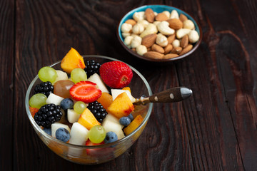 Bowl of healthy fresh fruit salad on rustic wooden background. transparent dishes. Selective focus, top view.