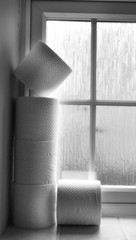 Black and white photo with toilet paper on the window sill.