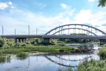 Big steel bridge over the river in Brest, Belarus, on the summer day. Architecture and nature in one picturesque lanscape