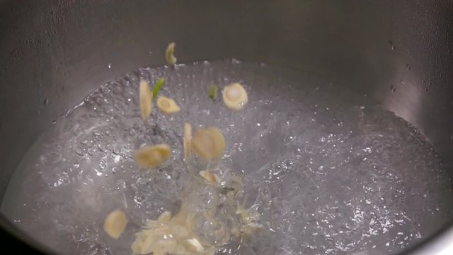 Finely chopped garlic falls into the boiling water.
