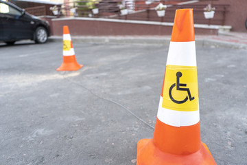 Traffic cones marking a parking spot for a disabled person on an asphalt road. Side view