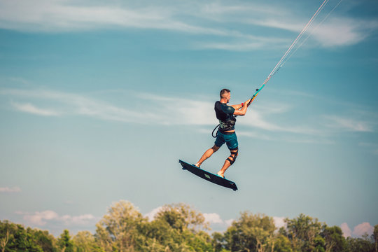 Professional kiter makes the difficult trick on a beautiful background. Kitesurfing Kiteboarding action photos man among waves quickly goes