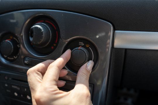 Woman hand switches the air conditioner modes on the panel in the car