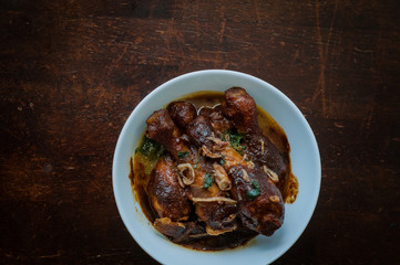 Malaysian dish of Ayam Masak Kicap or deep fried chicken in black soy gravy in a white bowl.