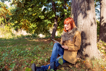 Woman with digital tablet in autumn park.