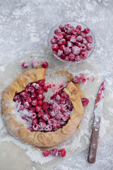 Homemade fruit pie (galette) made with fresh raspberries with powdered sugar on concrete background. Open pie, raspberry tart. Summer berry dessert. Flat lay. Empty space for text, copyspace.