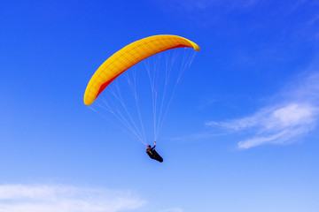 Paraglider flying on the background of blue sky with clouds, freedom concept.