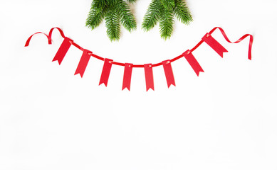 Christmas composition. Garland made of red small flags and red satin ribbon with fir branches on pastel background. Christmas, winter, new year concept. Flat lay, top view, copy space.