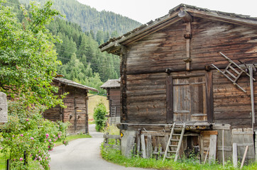Fototapeta na wymiar Wooden houses and sheds in rural village in Swiss alps in Valais valley on a summer day