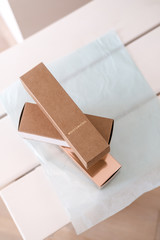 Set of three long package boxes in brown craft and rose gold color paper. Overhead, on white. Beauty, fashion blogging, minimalism concept