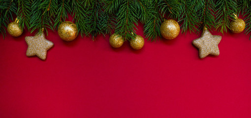 Christmas border. Fir branches and ornament on red background with copy space for your text. Christmas greeting card. Winter xmas holiday theme. Happy New Year.