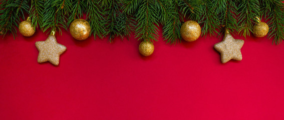Christmas border. Fir branches and ornament on red background with copy space for your text. Christmas greeting card. Winter xmas holiday theme. Happy New Year.