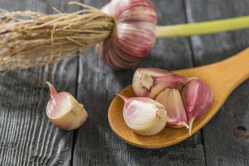 Wooden spoon with garlic on wooden table. Component of traditional medicine.