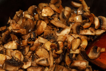 Fried champignon mushrooms in a pan closeup background texture