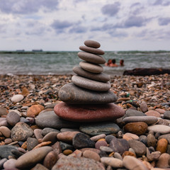 Sea stones stacked on top of each other against the backdrop of the sea on a clear sunny summer day.