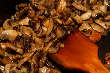 Fried champignon mushrooms in a pan closeup background texture