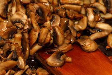 Fried champignon mushrooms in a pan closeup background texture