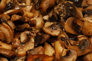 Fried champignon mushrooms in a pan closeup background texture