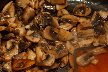 Fried champignon mushrooms in a pan closeup background texture