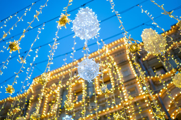 Festive street decor in winter holidays. Shining garland lights. Magical atmosphere. Blurred background city street with Christmas illuminations.