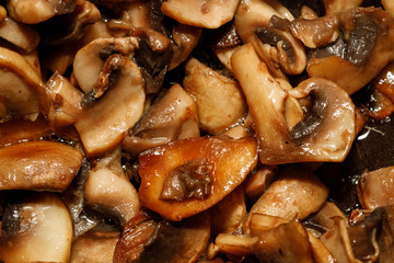 Fried champignon mushrooms in a pan closeup background texture