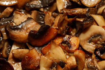 Fried champignon mushrooms in a pan closeup background texture
