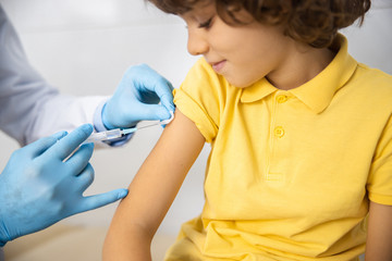 Calm boy being vaccinated by practitioner stock photo