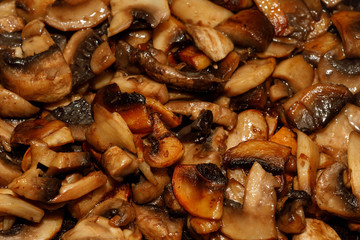 Fried champignon mushrooms in a pan closeup background texture
