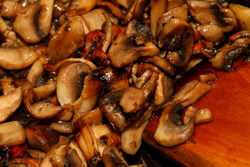 Fried champignon mushrooms in a pan closeup background texture