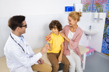 Happy boy getting sweet present in clinic stock photo
