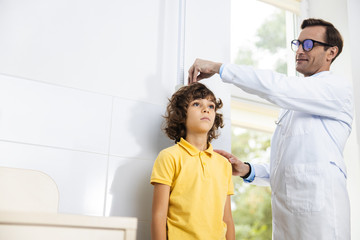 Obraz premium Jolly physician measuring little patient stock photo