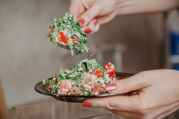 Woman  hands lay vegetable salad in round plate