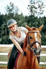 Foto op Canvas young girl rider in equipment on horseback. Horseback Riding. © Olek