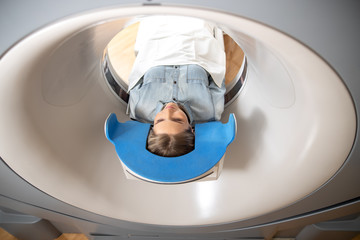 Young lady lying on table inside CT machine