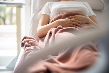 Young woman with her arms on belly resting in hospital room