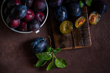 Colander with ripe juicy plums on table.